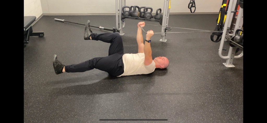 A person doing a banded deadbug exercise for core stability.